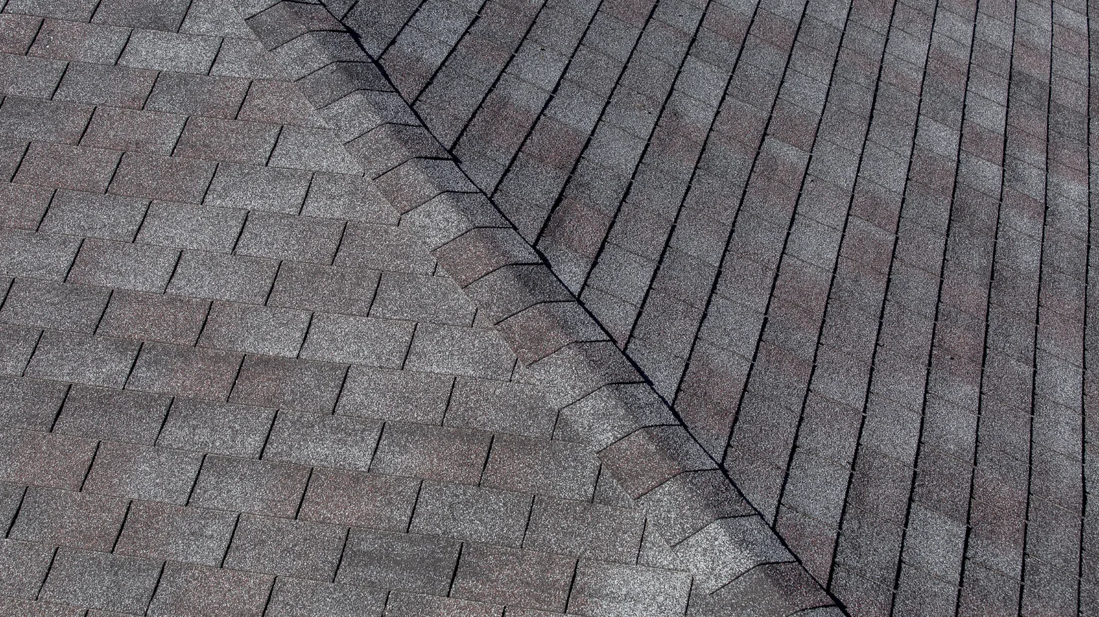 Hip ridge line crossing gray three-tab asphalt shingle slopes