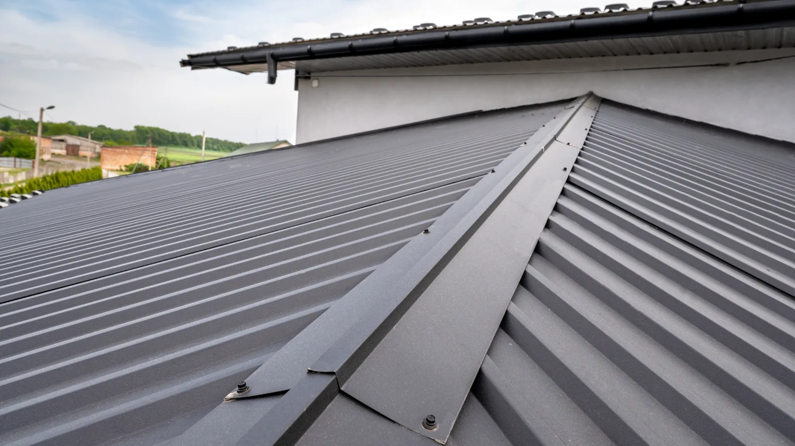 Dark metal roof panels joined at a hip with visible fasteners